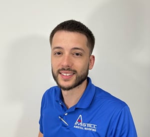 A smiling person with short hair and a beard wears a blue polo shirt with
