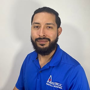 A man with a beard and short hair is wearing a blue polo shirt with the logo