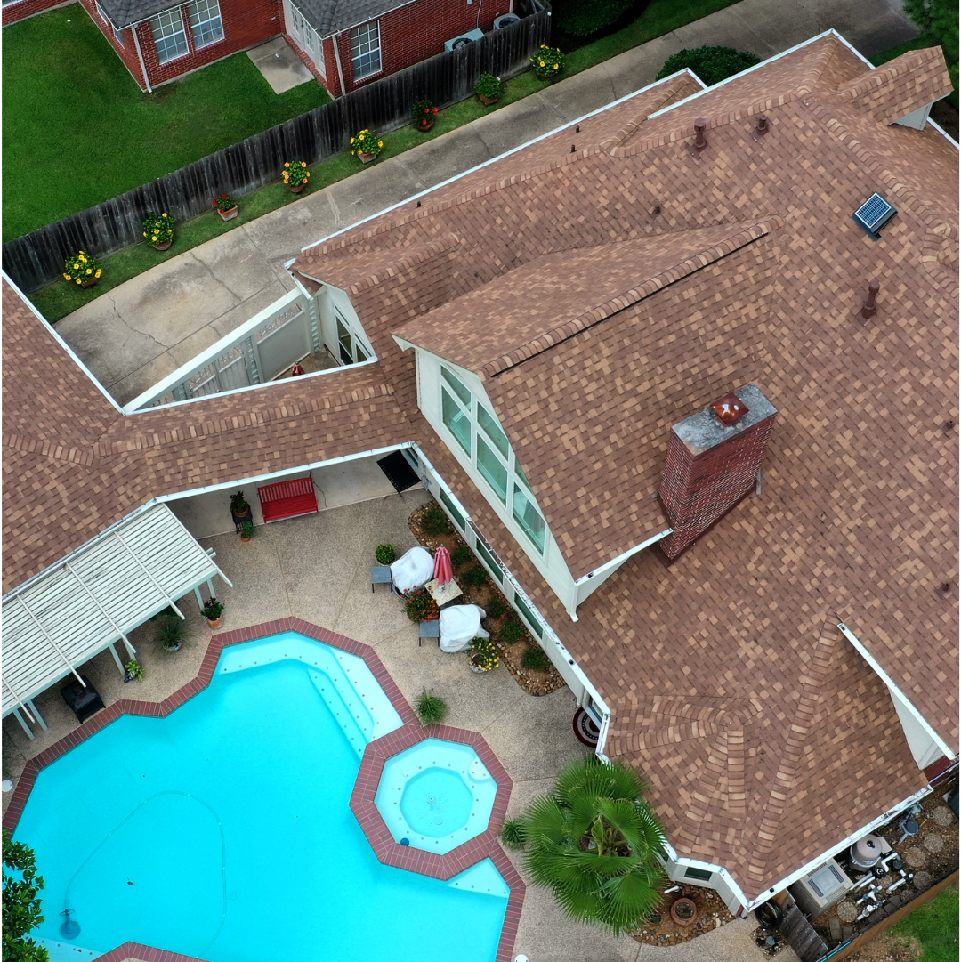 a house with a brown shingle roof, pool and a fence