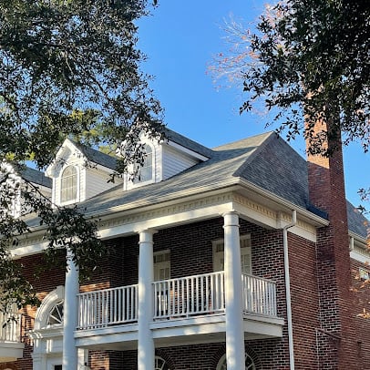 old colonial home with wrapped porch and gray shingle roof