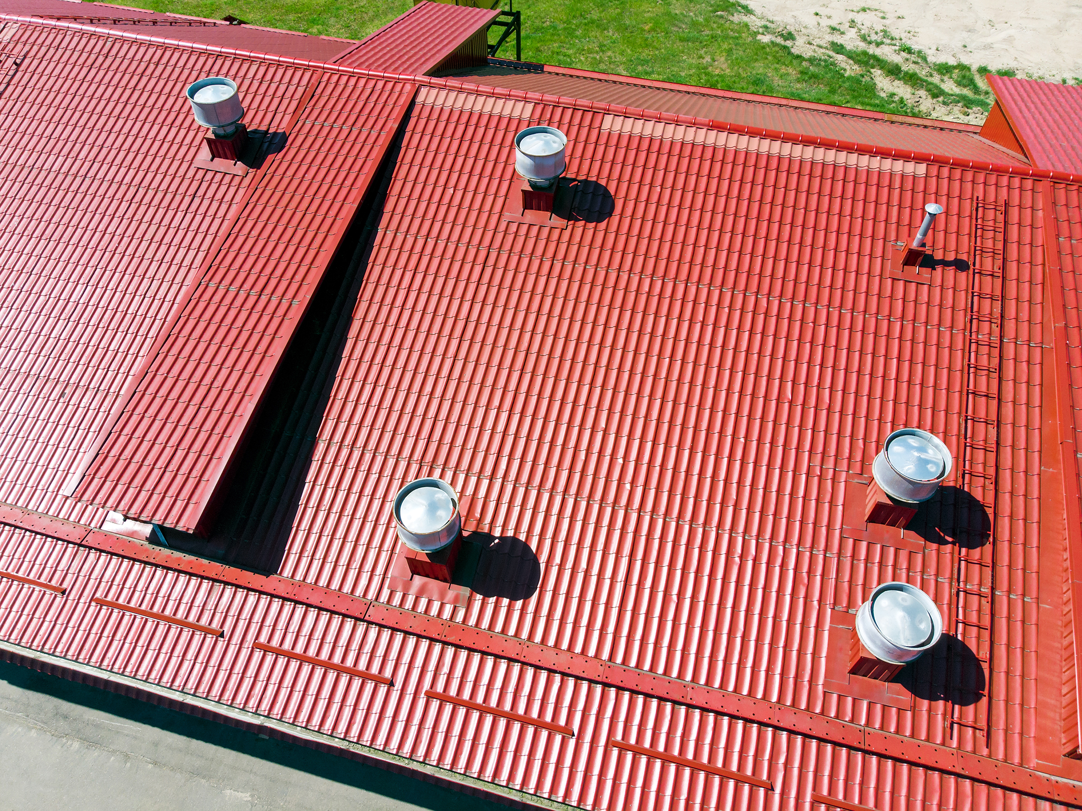 a red metal commercial roof with several vents