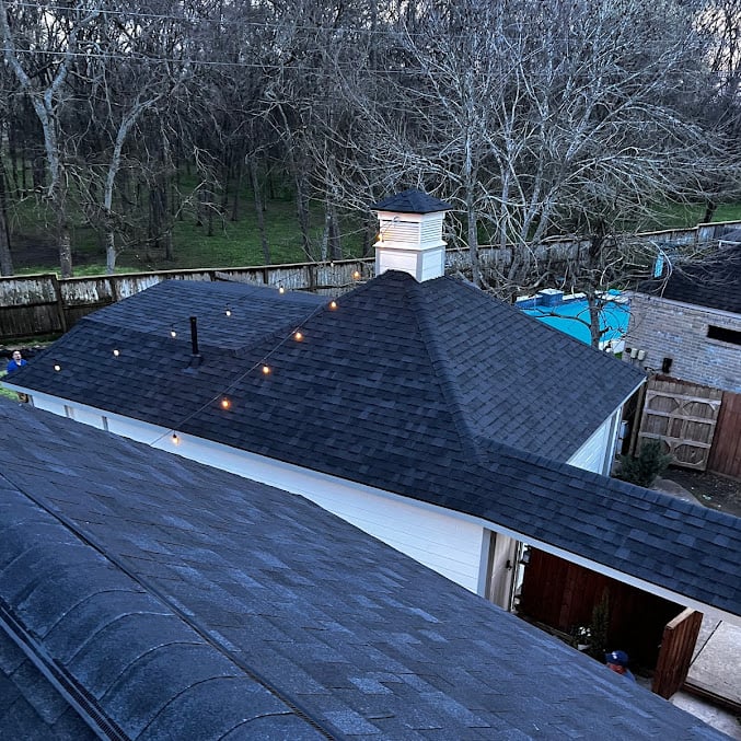 dark black shingle roof on a white home with pool in background
