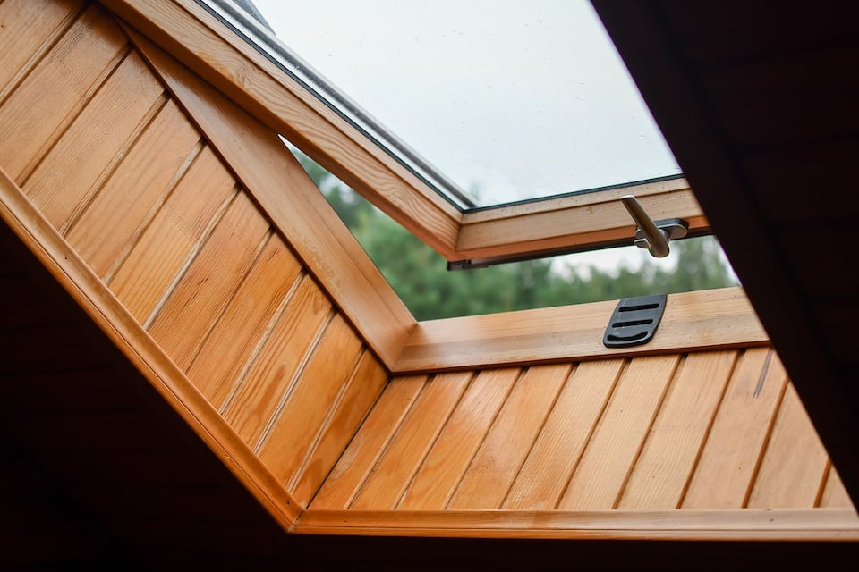 a vented skylight propped open surrounded by wood