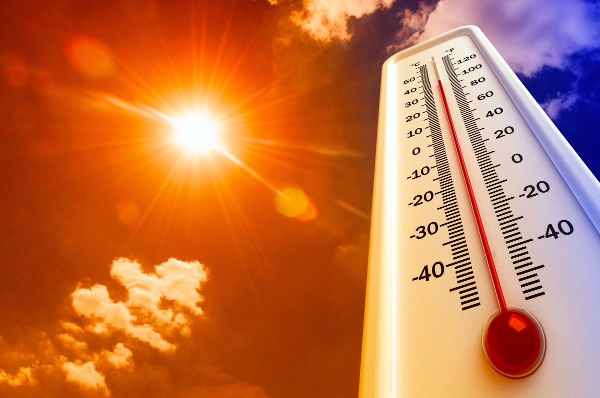 A brightly shining sun in a sky with scattered clouds is shown next to a thermometer displaying high temperatures, indicating a very hot day.