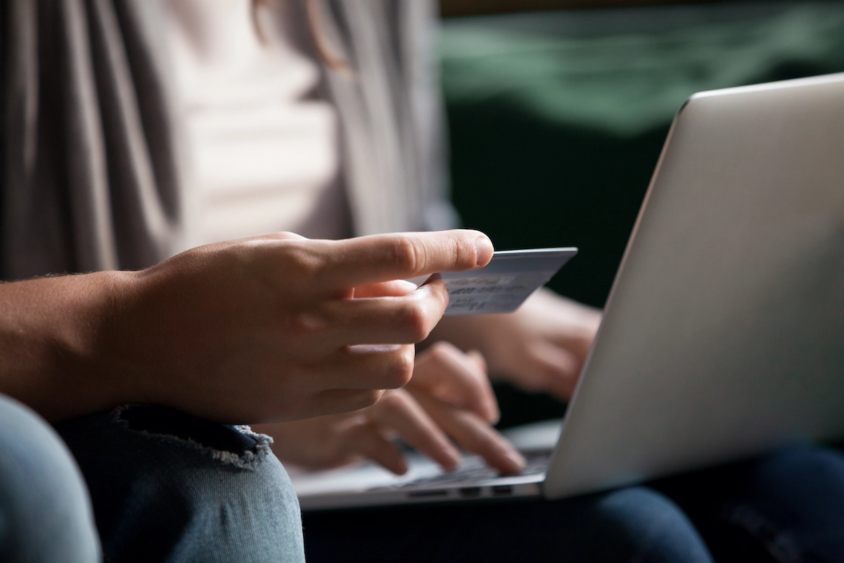 woman looking at credit card while putting information in computer