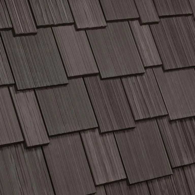 The image shows a close-up of a brown shingle roof with overlapping rectangular shingles arranged in a staggered pattern. The surface of the shingles appears textured with a wood-like grain.