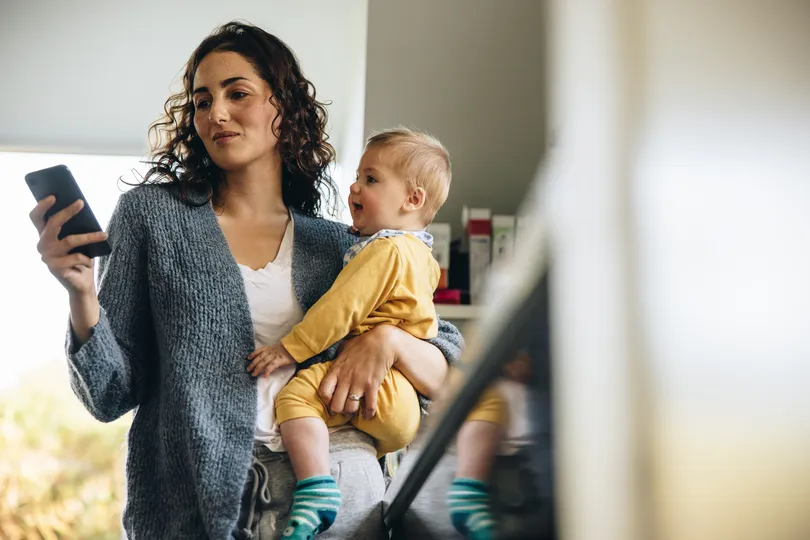 woman holding baby on the phone in kitchen