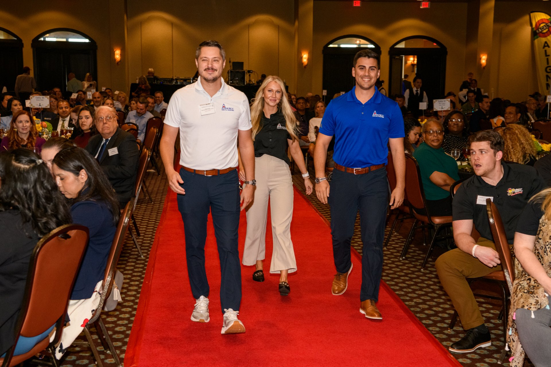 Sam Stilley, Lindsey, and Charlie walking down to receive the Best Roofer in Houston award from the Better Business Bureau, highlighting Amstill Roofing's commitment to excellence and customer satisfaction.