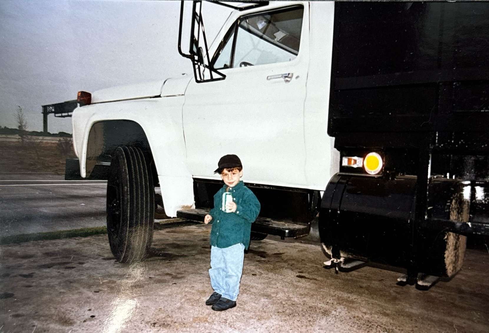 A young Sam Stilley stands next to a newly purchased roofing truck by his father. Amstill Roofing, a Houston roofing contractor since 1974, has been a family legacy, with Sam riding along on roofing jobs as a child and now leading the company as CEO.