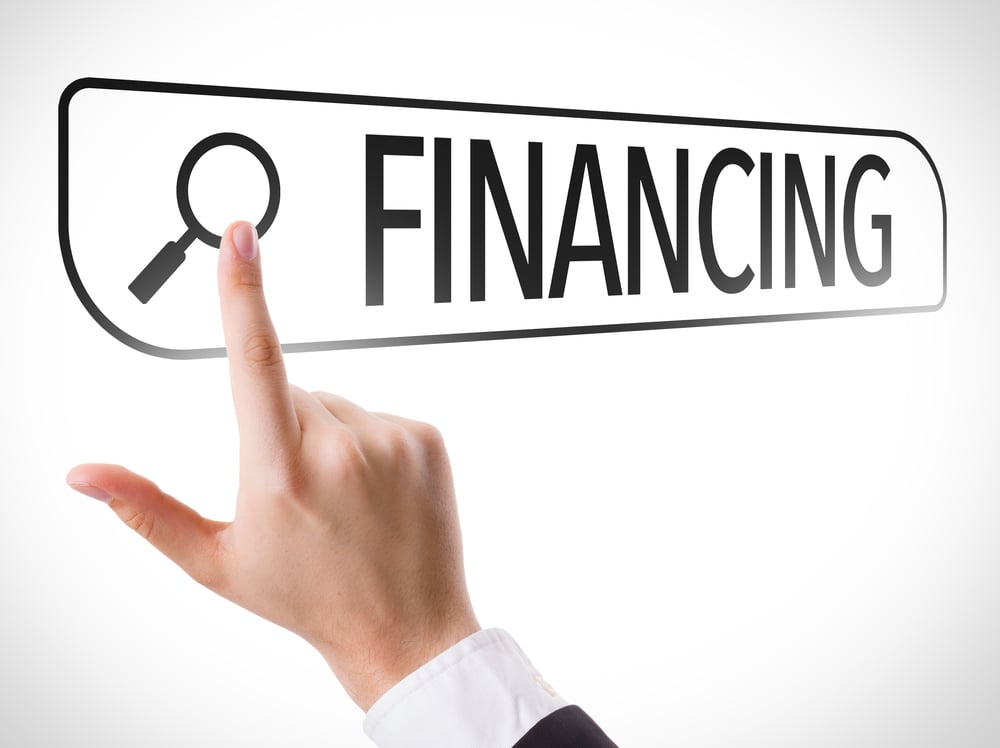 A hand pointing at a search bar with a magnifying glass icon and the word "FINANCING" written in bold black letters on a white background.